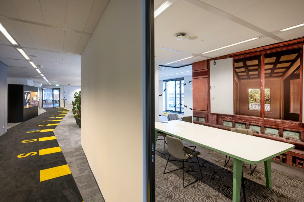 Moderne kantoorruimte aan de Piet Heinkade met een kleurrijke gang en vergaderruimte met muurdecoratie van een traditioneel houten interieur.